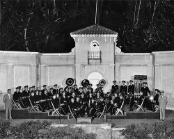 I've established that music was a life-long pursuit for my grandfather, from his youth in New Hampshire to his final days in North Carolina. But someplace in the middle, he and my grandmother spent a number of summers in South Dakota. This picture of the Sioux Falls Municipal Band dates from 1949 or 1950. 
Here's the line-up for the band, by tier: 4) Ed Paul (standing), Gossman, Smith, Hoover, Branch, Susede (?), RIchardson. Ellis, Jackson, Friedhoff, Alger, Pruner, Marker, Niblic (?), Kittleson, Miller, Henegar. 3) Madeck, Littlehang, Barnett, Askew, Little, Anderson, Lorenson (?), Brooks, Krumrai, Ewing. 2) Larson, Pace, Colwell, Hanson, Hoyt, Weber, Richardson, Wagner, Morgan, Griffith, Lias. 1) Palmer, Tyler (my grandfather), Olsen, Foss. Tietjen (Standing at right?) Cor. not in picture. View full size.
Sioux City is in IowaSioux Falls is in South Dakota.  The residents of Sioux Falls would be thoroughly upset if their city was confused with Sioux City.  Sioux City residents would probably be flattered.
Mea CulpaThanks, anonymous. It's right there in the photo -- Sioux Falls! If I'd only thought to trust my eyes... but my fingers often seem to have a mind of their own.
Bandshell still in useSioux Falls still maintains and uses this bandshell, in Terrace Park on the near north side of the city. A beautiful park with Japanese Gardens. If  you visit Sioux Falls, be sure to find this little gem.
(ShorpyBlog, Member Gallery)