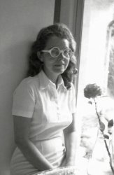My always-the-fashion-plate mother poses with a rose in the kitchen of our third home, which was in Haverford, Pennsylvania. Her red hair now hangs down the way it did when she was a child. Her big, round, oversized glasses were as trendy as glasses came in those days. Not sure which of our family members took the photo. Scan was made from a Polaroid print. 