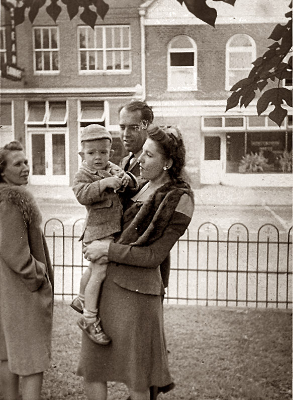 Dad being held by my grandmother in the early fall of 1943 in my great-grandfather's front yard on West Main Street in Charlottesville, Virginia. Grandmother's brother and his wife are also pictured. Great-Granddad's business - the Model Steam Laundry - is in the background across the street. 