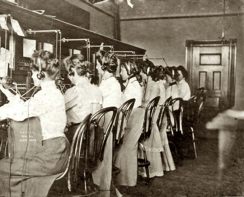 Telephone operators in Keene, N.H., probably about 1900. Though the picture is not labeled, I'm pretty sure the third girl from left is my Great Aunt Mabel Perry (née Carpenter). The book held upright in the lap of the first girl is stamped "N.E.T &amp; T. Co. Official Tarif Book."
