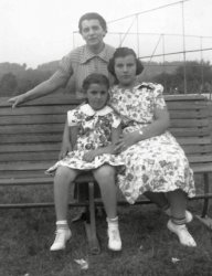 My then seven-year-old future mother sits on a park bench with her fourteen-year-old sister Harriet, while their mother Marie stands behind them, and not one of them has even a hint of a smile.