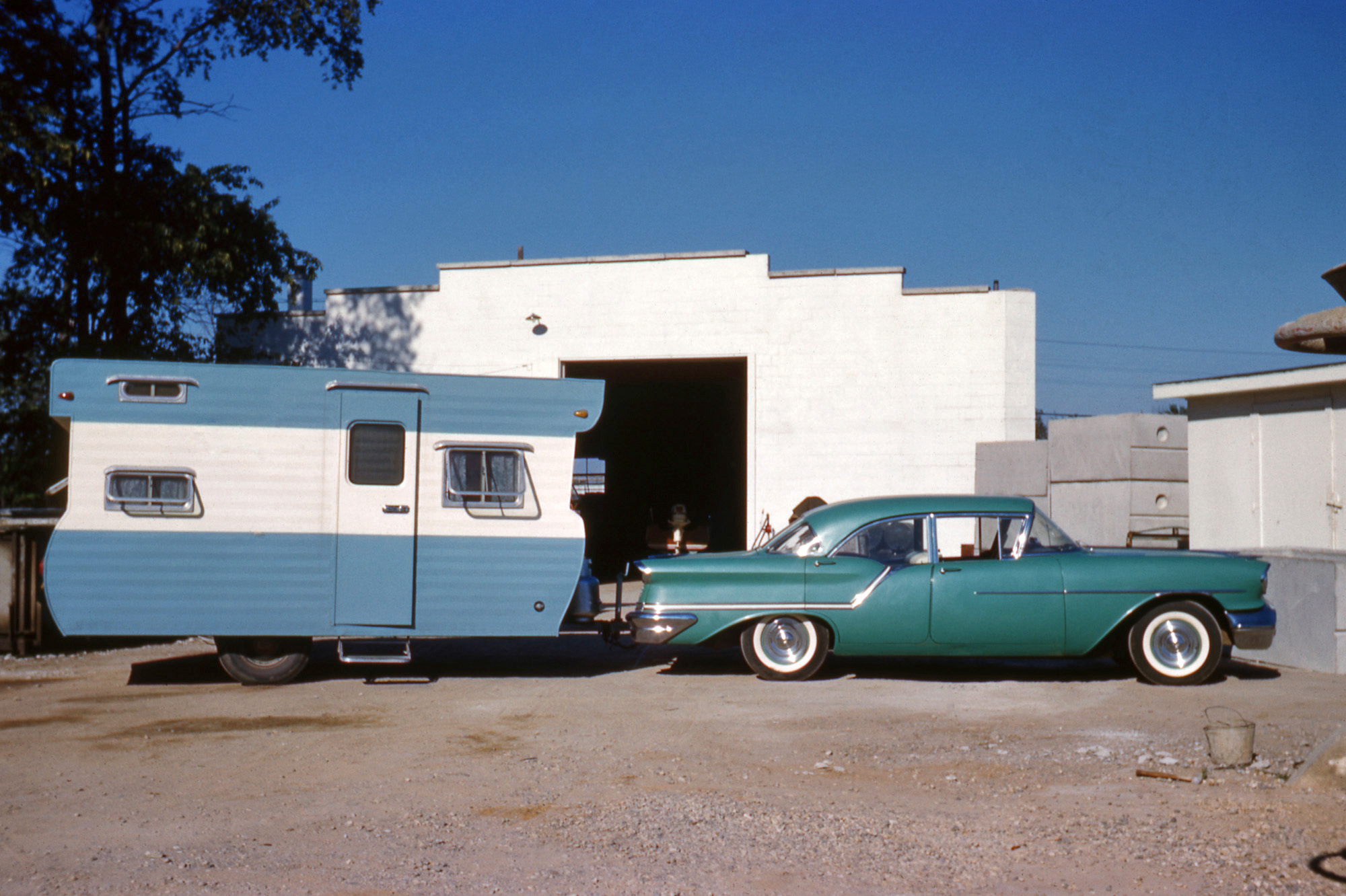 I don't know much about the photo other than it was taken in Holland, Michigan, at my great-grandpa's business where they made and installed cement septic tanks. You can see some toward the right of the photo. The car is a 1957 Oldsmobile. Also note the boat in the building. 35mm color slide. View full size.