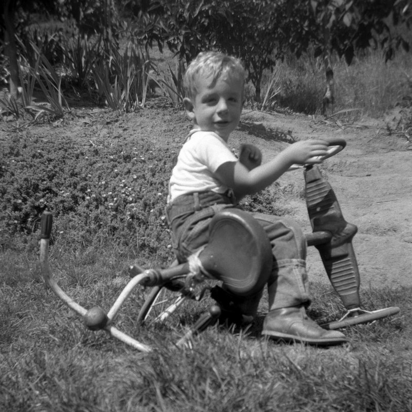 I realize this isn't how most kids would use a tricycle. But you see, what I really wanted to do was play "driving a car," only I didn't have one of those. So I made do with my big brother's old trike; I'm pretending the real wheel is the steering wheel. You see. Around 1949. Look at those cuffs and that waistline; my mother was planning on my getting a lot of use out of those jeans.

