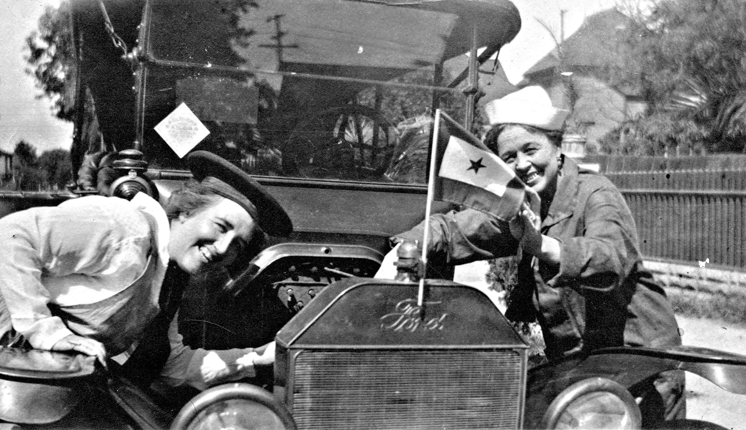 This is from a 2.7" x 4.5" paper photo found in an antique store. It's unmarked and I have no idea of its history, but that does appear to be Mrs. Roosevelt on the right? The car, style of dress and the service flag would indicate WWI era. View full size.