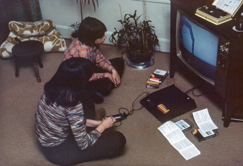 Continuing on our theme of the ancient-1970s history of consumer electronics, here's my niece and nephew playing with my Fairchild Channel F video game. According to Wikipedia, it was the first ROM cartridge-based video game console, selling for $170 when released in 1976. It was a color system, despite the appearance of the screen. I'd intended using it with my Advent VideoBeam projection TV, but the Channel F's signal wasn't sufficiently up to snuff sync-wise (or something) to satisfy the VideoBeam. Shortly after this, I got an Atari 2600 that worked with it. I myself never really got heavily into video gaming, other than a brief and mild addiction to Atari's Space Invaders and Breakout. Mainly I was just fascinated by the big, colorful graphics whizzing around on the giant VideoBeam screen. This bounce-flash Kodachrome was considerably underexposed, so I had to boost it quite a bit. Oh, and feel free to grab a chocolate from the Whitman's box. View full size.

