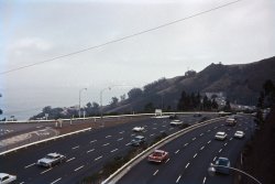 October 1964. U.S. 101 above Sausalito, Calif., the Waldo Grade approach to the Golden Gate Bridge. Similarities after 44 years: same number of traffic lanes. Differences after 44 years: many more cars, but none of them have fins. My color slide with Montgomery Ward brand film. View full size.
Chrysler or DeSotoCan you blow up that gray car on the left? At first I thought 1961 Chrysler but it looks a little like it has the 61 DeSoto's weird oval upper grille.
[I was wondering the same thing. - Dave]

TailfinsAbout 7½ years earlier you might have caught our brand-new, highly-finned, White-over-Turquoise '57 Chevy Bel Air along there as we trekked to SF from Novato to show Golden Gate Park etc. to my maternal grandmother visiting from Australia.  It seemed that half of the time the GG Bridge
towers were enshrouded in fog!
Yep, a DeSotoChryslers didn't have that pattern of two-tone (sides one color, top different).
[If I may interject: There's no two-toning on that car. And I'm pretty sure there were no 1961 DeSotos with the two-tone paint scheme you describe, either. - Dave]
I should be able to identify the first car on the left, but I'm not sure -- the strake-fold above the rear wheels should be distinctive. After that:
The aforesaid Desoto;
Black '57 Chevy Nomad;
VW Karmann Ghia convertible;
'63 Chrysler;
Pre-1950 Ford pickup;
Another black '57 Chevy, this one a sedan;
'52 or '53 Mercury.
The black blob just before the curve is unidentifiable, at least by me.
Going the other way:
The blue pickup under the lamppost -- ??
Red '59 Chevy El Camino -- if you had that car now, you could sell it and buy a house;
The others I can't do. I think the white car on the right is a brand-new Pontiac Le Mans.
Regards,
Ric
Point Of Viewtterrace, were you standing on the Wolfback Ridge overpass when you took this?
Waldo viewpointYep, the Google street view from the overpass matches; those trees in the '64 shot have now grown so you can't see the tunnel from there. BTW, I remember when that southbound bore was the only one, with both directions, four lanes undivided, going through. An exciting ride, especially on rainy winter nights. And noisy because those were the days when you were expected to violate the no-horn-blowing-in-tunnels stricture. Sometimes I even could pester my father into a beep or two.
Fifty-NinerNoticed the '59 El Camino right away. I owned one for about four years but had to sell it in 2005. Dang I miss that thing. Nice Photo!
(ShorpyBlog, Member Gallery, Cars, Trucks, Buses, tterrapix)