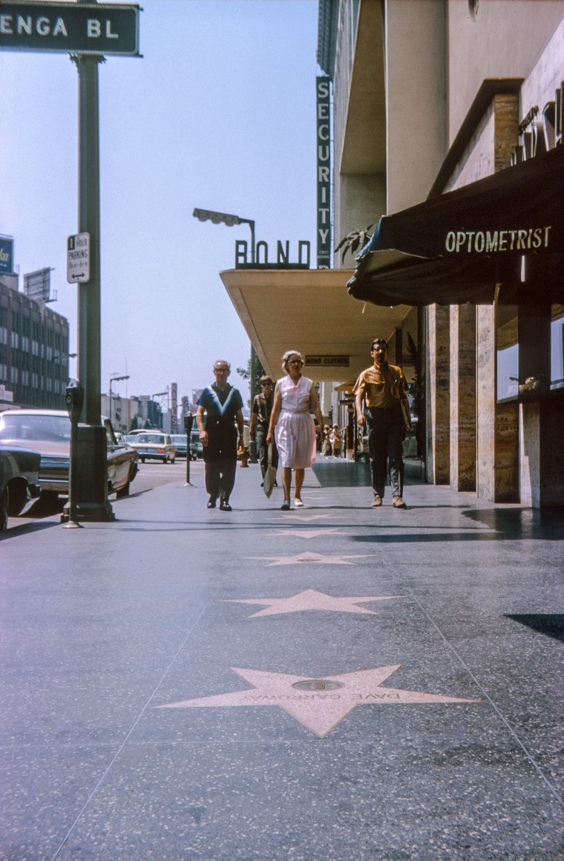 The summer of 1965 finds my father, mother and brother on location in Tinseltown at 6353 Hollywood Boulevard. We didn't see any celebrities, but we did come across record stores, and my brother is clutching two bags of our gleanings therefrom. What my parents did while we gleaned I'm not sure, but no doubt they met the situation with their usual forbearance. Here in my Kodachrome slide they're approaching one of Dave Garroway's two stars - this one for radio - on the Walk of Fame. Garroway, some might remember, was the first host of NBC's Today Show. Later, they were at Hollywood and Vine, where I was snapped in 1963. View full size.