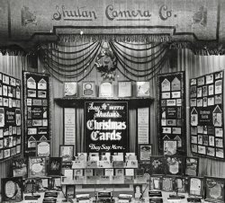 c1930s. A storefront window display of Shutan Camera Co. on West Washington Street in downtown Chicago. My grandfather Edwin Shutan offered a large selection of quality Christmas cards and fine writing instruments - and always arranged the displays meticulously. View full size.
They Say MoreI love the logic: not only should you say it with Shutan's Christmas cards, but you should do it because they say more.  Than what?  Other cards?  Or not using cards at all?  (Maybe I'm over-thinking it, but I still love that message.)
As for the pen-and-pencil sets and pen stands, I'm sure they'd come in handy for those Christmas cards, but I always thought of them as the classic Bar Mitzvah gift.
(ShorpyBlog, Member Gallery)