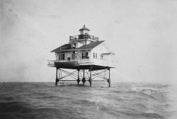 Location: Unknown. Date: Unknown. This home appears to be a true light house. One can imagine it didn't last many storms. View full size.
A Screw-Pile LightThis is an example of a screw-pile lighthouse, of which indeed only a few remain. The did indeed screw the pilings into the bottom. They were particularly popular in the Chesapeake Bay region, but they saw use in NC and along the gulf coast too, and there are a number of monster versions along the Florida coast.
They were actually pretty tough in the face of storms, particularly since they were mostly used in more sheltered locations where they didn't have to deal with ocean storm waves. Their real nemesis (besides the USCG, which tended to remove the house once they became automated) was ice, which would ride up the piles and push the house off the foundation. There were several instances in which the house ended up being carried down the bay, occupants and all.
I can't identify this particular light with any certainty, but it might be the Lower Cedar Point Light on the lower Potomac River.
Croatan Shoal Light, NCIt's the Croatan Shoal light in North Carolina. Click for info.

I know you saidit was waterfront property but this is rediculas.
[We used to summer at Rediculas. - Dave]
(ShorpyBlog, Member Gallery)