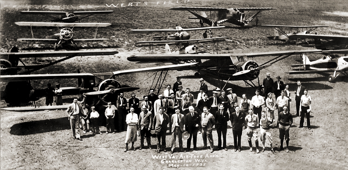 1932. Wertz Field, just outside Charleston, W.Va., served as its airport long before Kanawha (now Yeager) was built. My uncle Oral Hamrick is standing with arms folded in front of his plane, "National Commander." The owner, Louis Johnson, was Secretary of War during WWII. Six months after this photo was taken, Oral was killed when the plane crashed in a snowstorm. View full size.