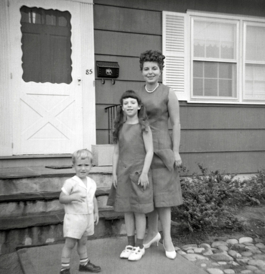 As I have said before, my mother was decidedly Mrs. Sewandsew. Along with making us matching RCA Picnic shirts in Princeton, she made matching red dresses for her, me, and a tiny one that was an exact replica of ours for my Barbie doll. These were not special occasion clothes. They had great big pockets with pointed tops (since she knew I would wear, and wear, and wear anything with a big pocket for me to stash stuff in) and were of a pattern she designed which she identified as princess line. And yes, the faux pearl beads, and medium heels were the way she dressed on a regular day. She did not have house dresses or cleaning house clothes. 

Baby boomers will recognize the square object on the steps that you can see between me and my brother as a milk box. Each morning a man from a local dairy company delivered fresh milk to our house, using it. 