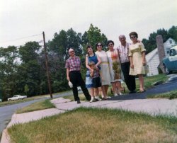 Most people would say this is a crooked picture of a family posing in front of a lawn that desperately needs watering. But it is really a picture of our 1955 Pontiac, the only used car my family ever had. When we moved from PA to NJ in 1962, my father sold our 1952 Studebaker. We took our 1960 Edsel. For some reason he thought we wouldn't need two cars. He was wrong.
So when he saw the Pontiac for sale, he bought it and brought it home, to my delight. It was a 2-door sedan with real leather seats, auto trans and radio. Some seams on those seats were coming apart. The radio did not work unless you went over a bump, then it did for 15 seconds.
It had an Indian face hood ornament that was supposed to light up, but it didn't. I loved that car, but I loved the Edsel more, so in 1967, when he said the first car to need any repair at all would be replaced, I made sure it wasn't the Edsel.
As for the people to the left of the Pontiac, they are my father Howard in the plaid shirt, my four year old brother Iden; me; my father's sister-in-law Mildred, who went by the name Margaret because she couldn't stand the name Mildred; my father's older sister Bertha, who went by the name Buddy, because she couldn't stand the name Bertha; Buddy's husband Abe, who couldn't stand me and my brother's names, so called me Princess and Iden "Johnny Boy." And my mother, Arlene who, as usual, is showing off a dress she designed and made (out of a checked fabric Abe gave her the year before). Taking the photo is my father's older brother Norman  who kept his first name, but changed his last name. View full size.
Every familySo glad to see every family has the same crazy people.Many of my relatives have other names. My cousin Lola goes by Junie because my Uncle wanted a boy "Junior". Whatever!
(ShorpyBlog, Member Gallery)