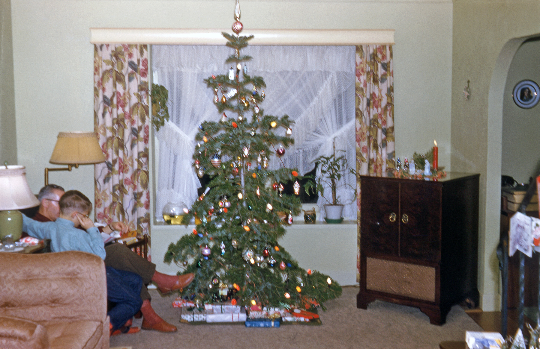 1955. My brother takes a Kodachrome flash shot, and jiggles the camera a little. I'd like to say my father is reading me a Christmas story, but that never happened. Little did I realize back then how great those drapes were. That floor lamp is in my living room right now, and I also have the plastic Wise Men over on the Motorola. It's hard for me to think of something plastic as being antique, but it's 53 years, so...  View full size.