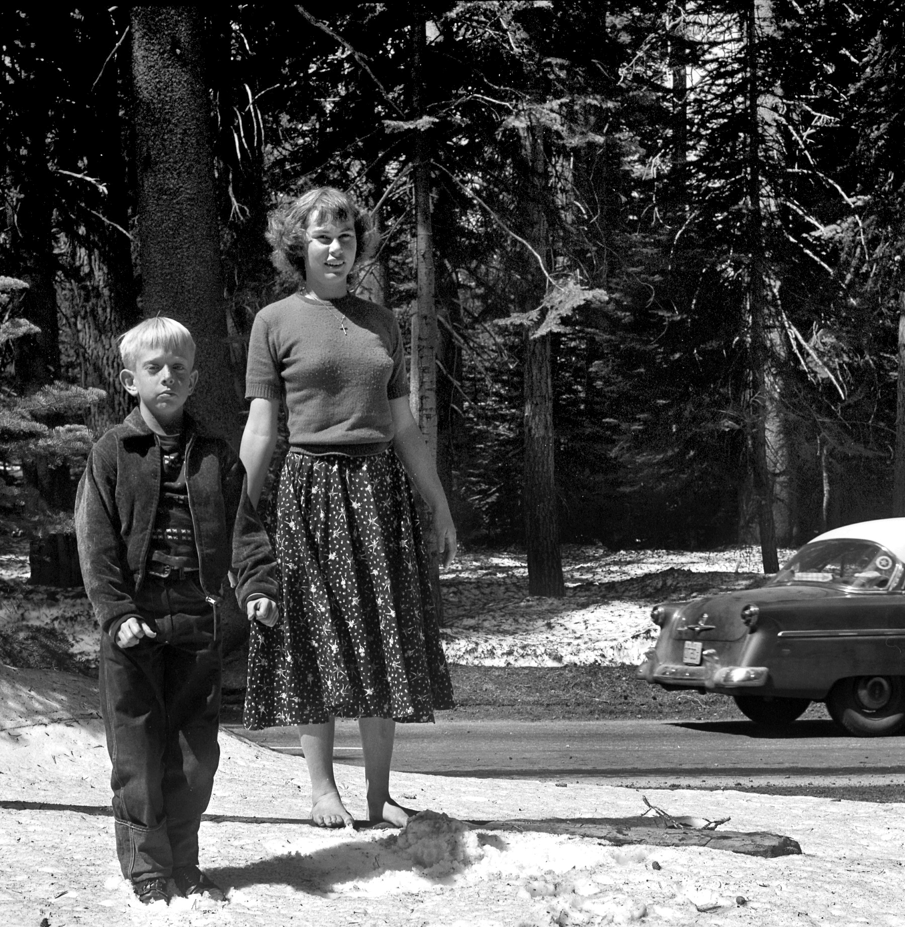 Here we see our two companions yet again, albeit one of them with an odd choice of footwear (or lack thereof). tterrace says the car is a 1954 Ford. View full size